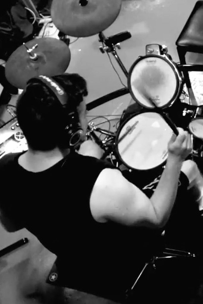 Image of hands holding drum sticks in front of drums